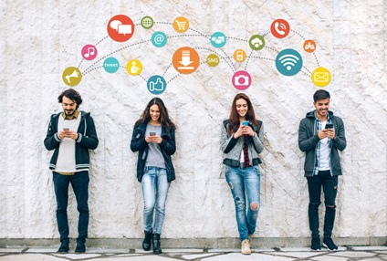 Four teenagers standing infront of a wall with various soical and online emojis above them linking them together